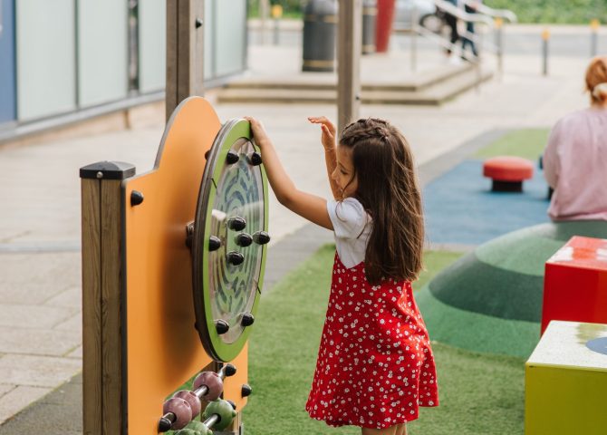 Child playing with educational outdoor playground equipment.